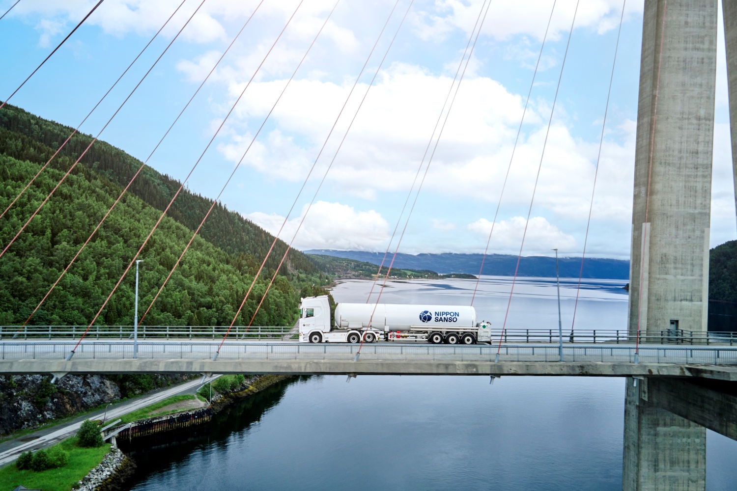 Autocisterna Nippon Sanso attraversa un ponte sospeso tra fiordo e foreste